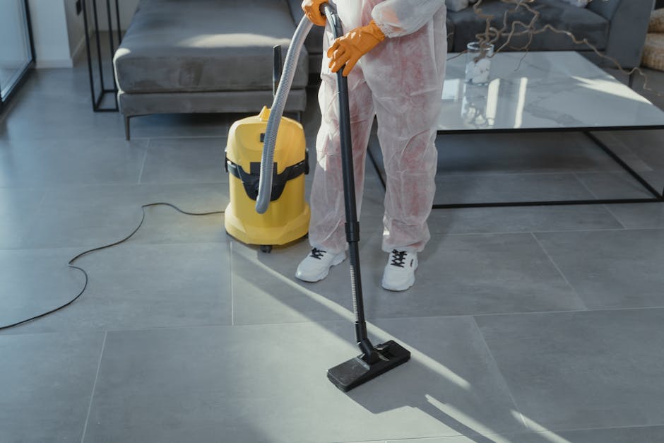 A person wearing yellow rubber gloves is holding a lightbox with the words 'CLEANING HOME' in bold black letters. The lightbox is placed on a surface in a well-lit room, emphasizing the theme of domes